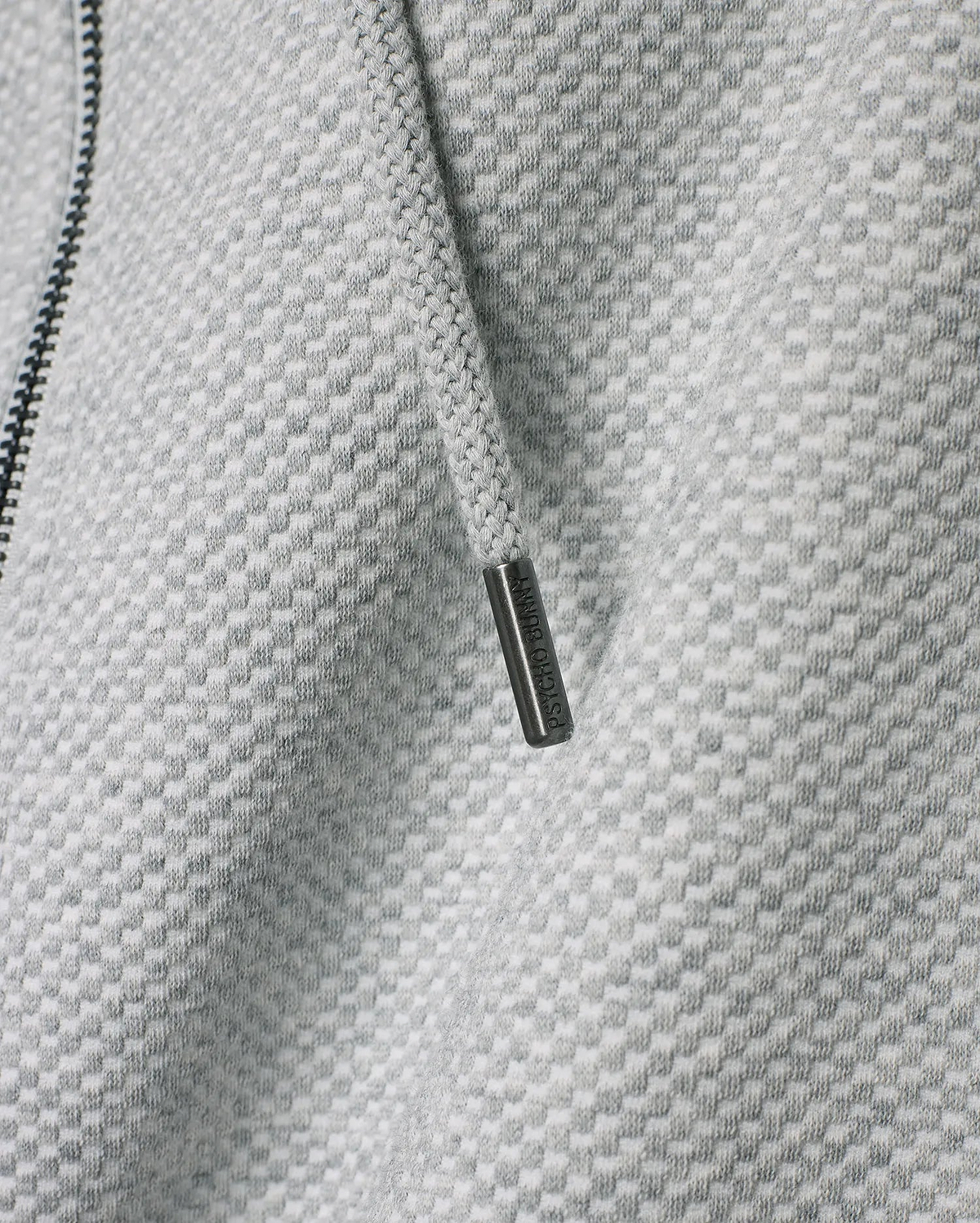 Mens Marc Textured Full Zip Hoodie in light grey with a distinct checkered knit pattern, featuring a dark zipper and a drawstring with an engraved Psycho Bunny metallic tip.