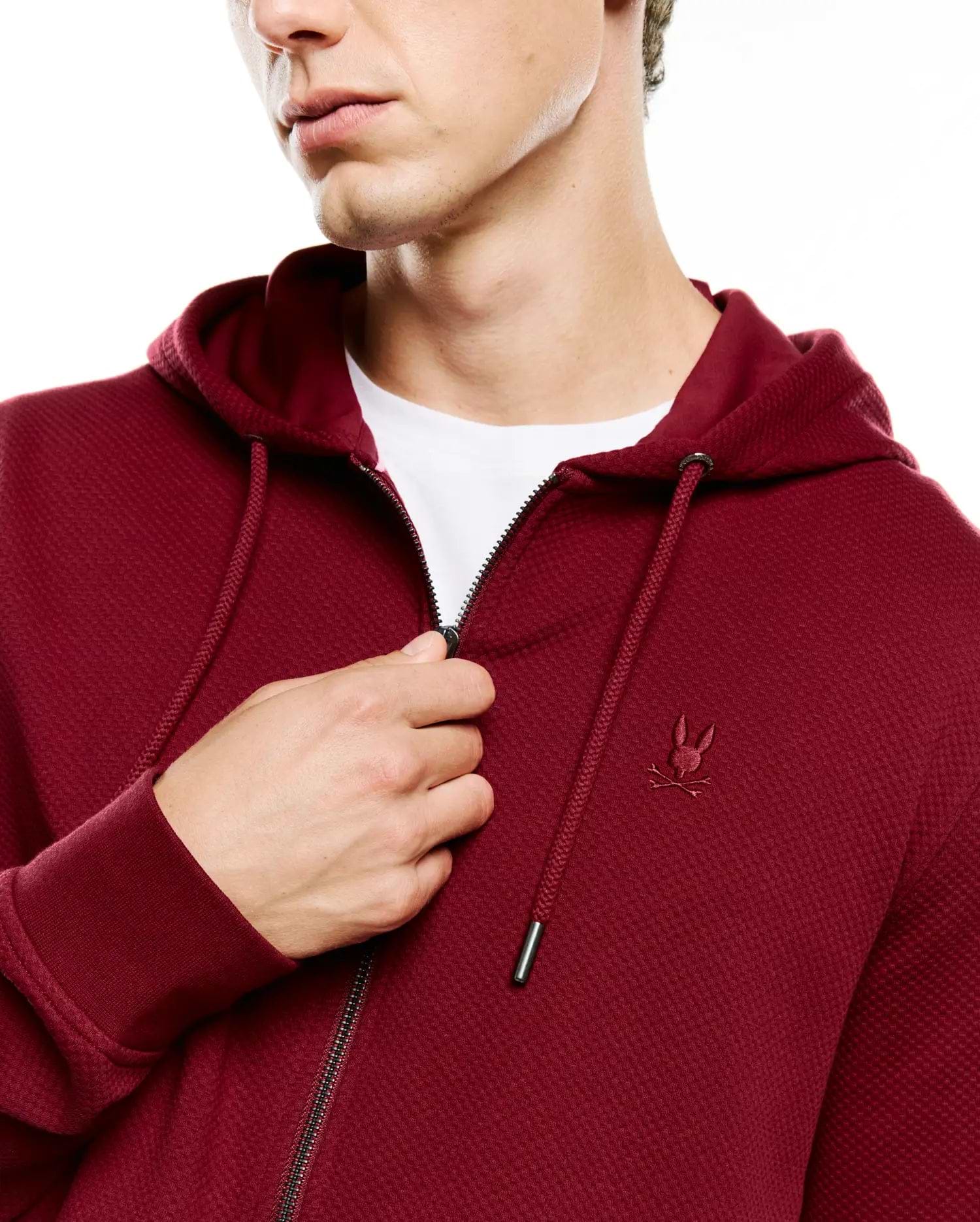 Mens Marc Textured Full Zip Hoodie in deep maroon, featuring a waffle knit texture, full zip closure, drawstring hood with silver tips, and a small embroidered Psycho Bunny skull logo on the left chest.