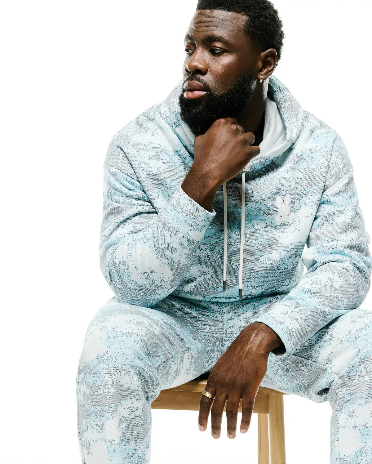 Men's Alfie All-Over Print Hoodie in light blue, white, and grey pixelated digital camo pattern, featuring a drawstring hood, relaxed fit, and small embroidered white Psycho Bunny skull logo on the left chest. (4)