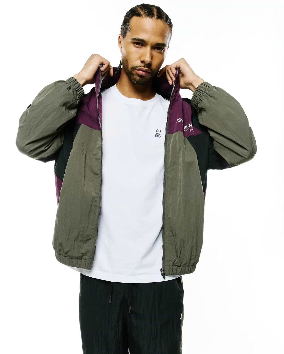 Mens Alder Nylon Colorblock Jacket: Relaxed fit olive green, purple, and black crinkled nylon full-zip jacket featuring a colorblock design, elastic cuffs, and Psycho Bunny text on the chest.