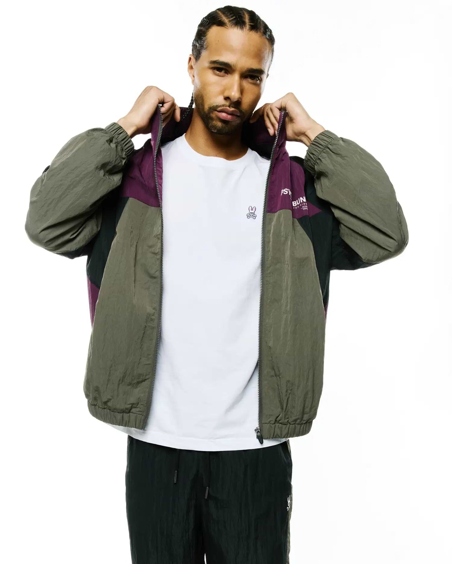 Mens Alder Nylon Colorblock Jacket: Relaxed fit olive green, purple, and black crinkled nylon full-zip jacket featuring a colorblock design, elastic cuffs, and Psycho Bunny text on the chest.