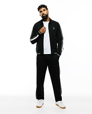 Black Mens Ceano Track Jacket and matching track pants, featuring white double sleeve stripes, single pant stripe, and small embroidered white Psycho Bunny skull logos on chest and thigh. Relaxed fit, smooth knit.