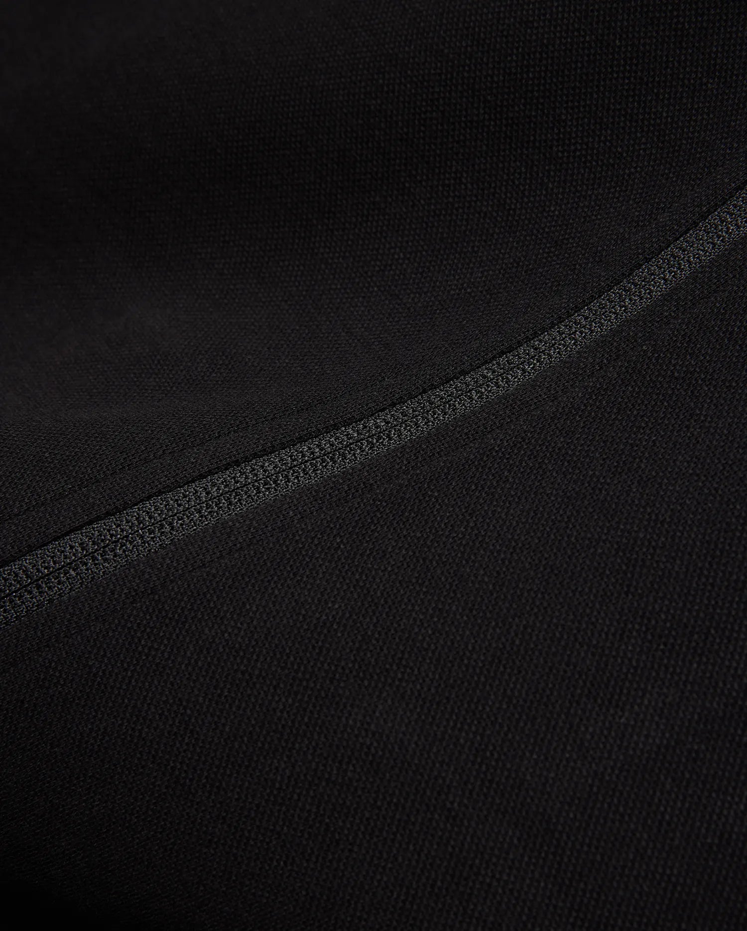 Black Mens Ceano Track Jacket featuring a smooth, finely textured knit fabric, accented by a prominent, precisely stitched flatlock seam running diagonally across the garment.