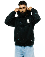 Mens Malcom Splatter Hoodie, a black relaxed fit soft jersey hoodie featuring a vibrant white and teal splatter print and a large white Psycho Bunny skull logo on the left chest.
