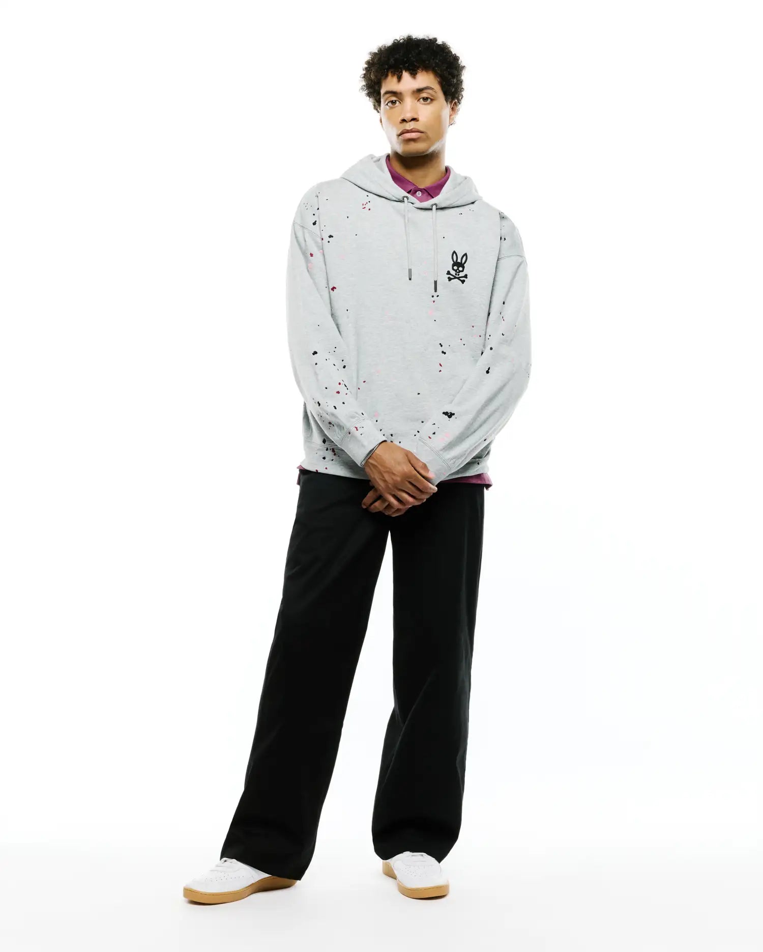Mens Malcom Splatter Hoodie, a relaxed fit heather grey French terry hoodie with colorful paint splatter accents, featuring a large black embroidered Psycho Bunny skull logo on the left chest.