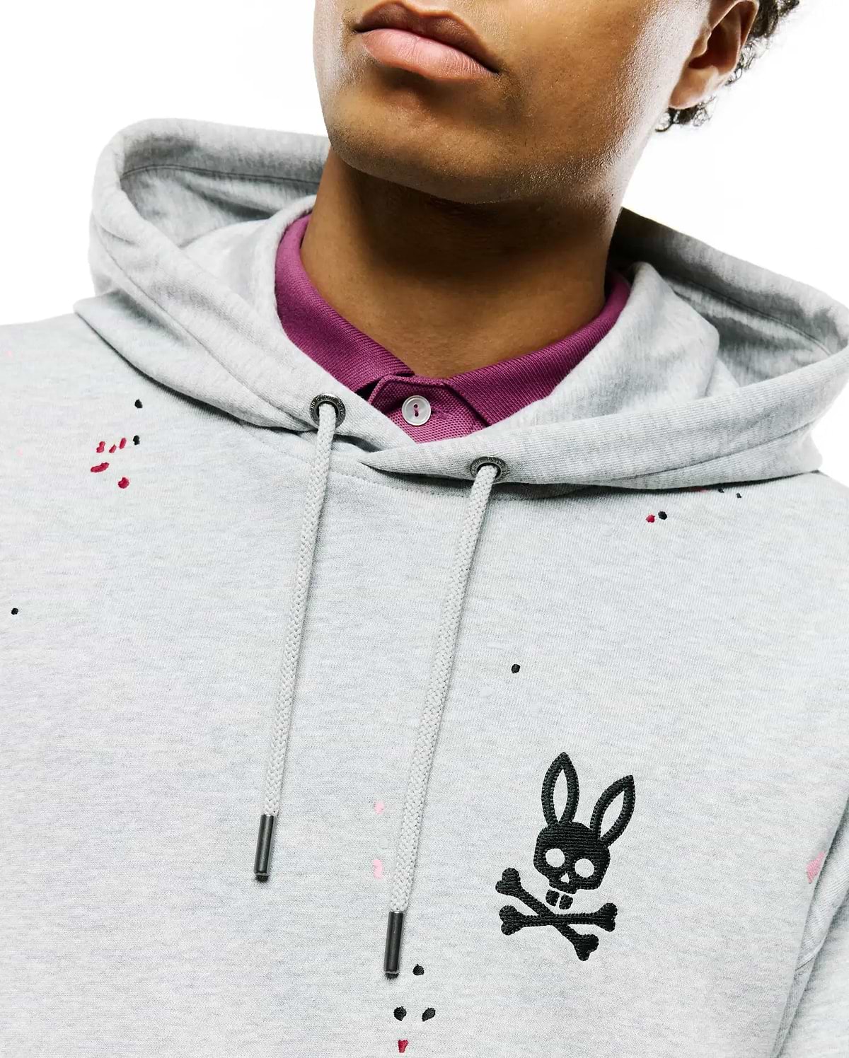 Mens Malcom Splatter Hoodie, a light grey french terry hoodie with a classic fit, featuring a black embroidered bunny skull logo on the left chest, drawstring hood, and colorful splatter paint accents.