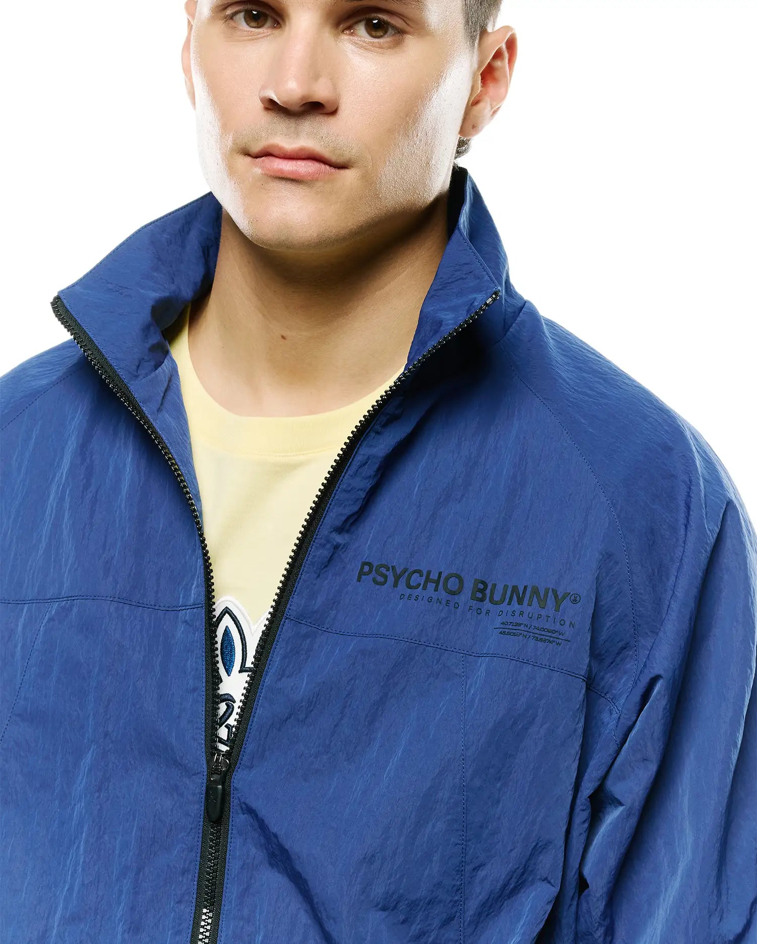 Mens Alder Nylon Jacket, royal blue crinkled nylon, relaxed fit, with a full black zipper, stand collar, and large black Psycho Bunny text logo, Designed For Disruption slogan, coordinates on left chest. (3)