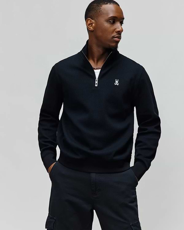Black MENS MAXTON WAFFLE 1/4 ZIP pullover with a classic fit, featuring a textured waffle knit, silver zipper, and a small white embroidered Psycho Bunny skull logo on the left chest.