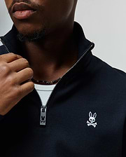 Mens Maxton Waffle 1/4 Zip in black waffle knit, featuring a stand-up collar, silver 1/4 zip with a branded Psycho Bunny pull, and a small white embroidered bunny skull logo on the left chest.