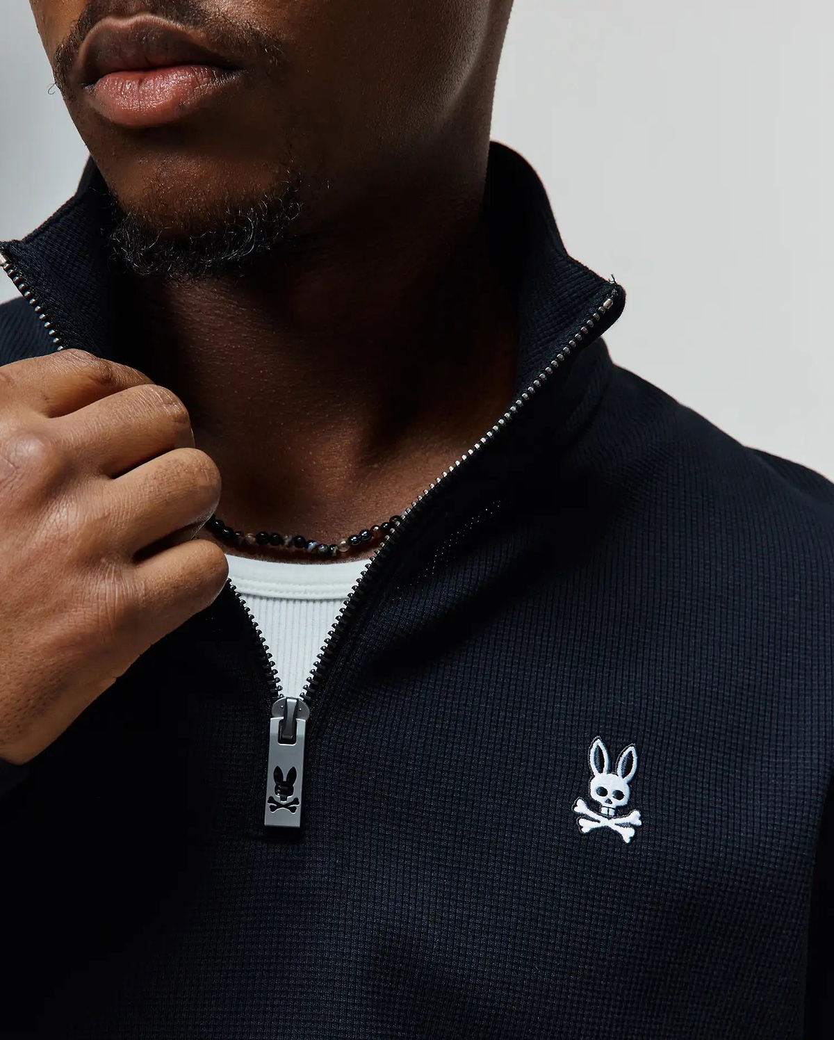 Mens Maxton Waffle 1/4 Zip in black waffle knit, featuring a stand-up collar, silver 1/4 zip with a branded Psycho Bunny pull, and a small white embroidered bunny skull logo on the left chest.