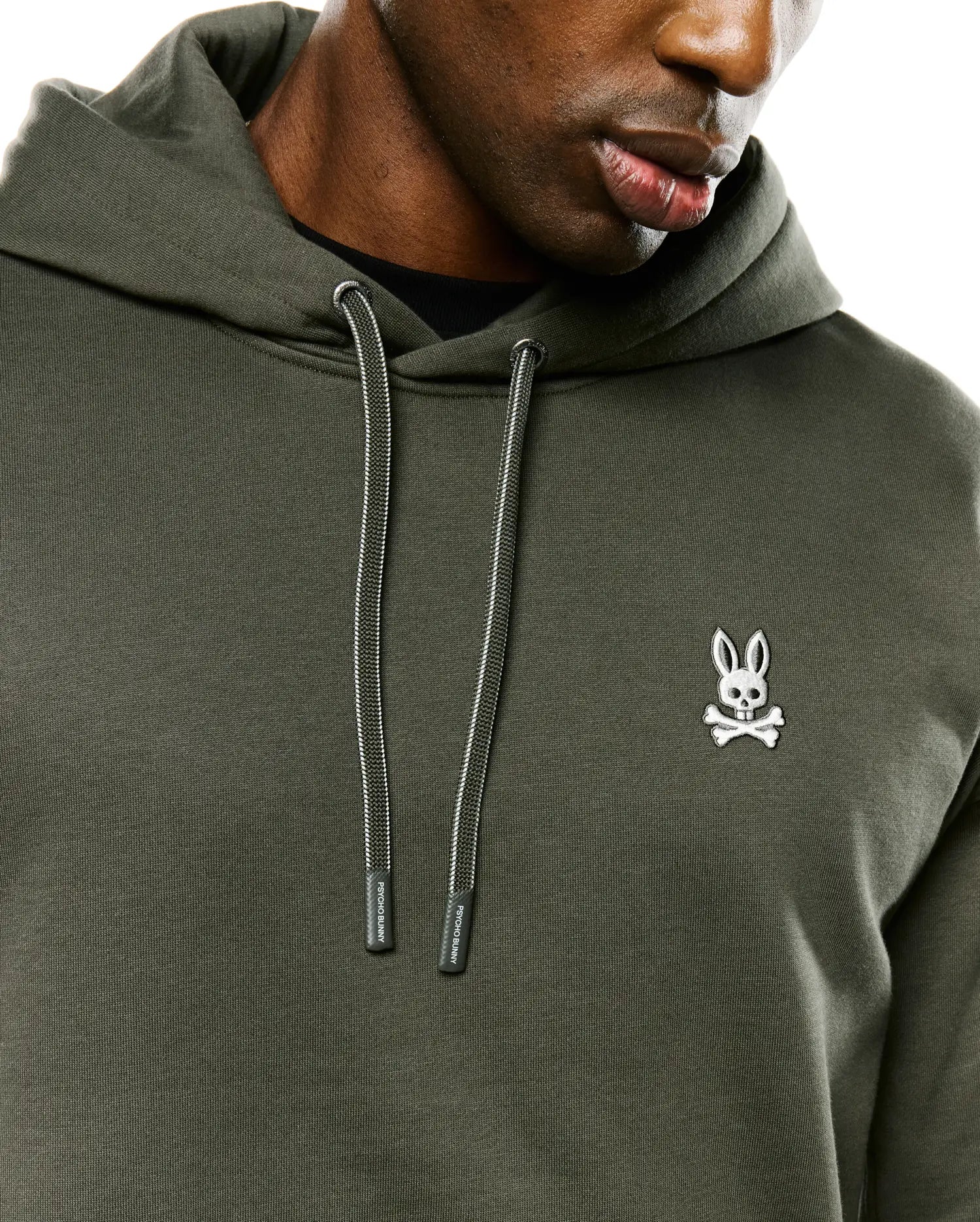 Mens Terrence Brushed Fleece Hoodie, dark olive green brushed fleece, with a white embroidered Psycho Bunny skull logo on the left chest and striped drawstrings with branded tips.