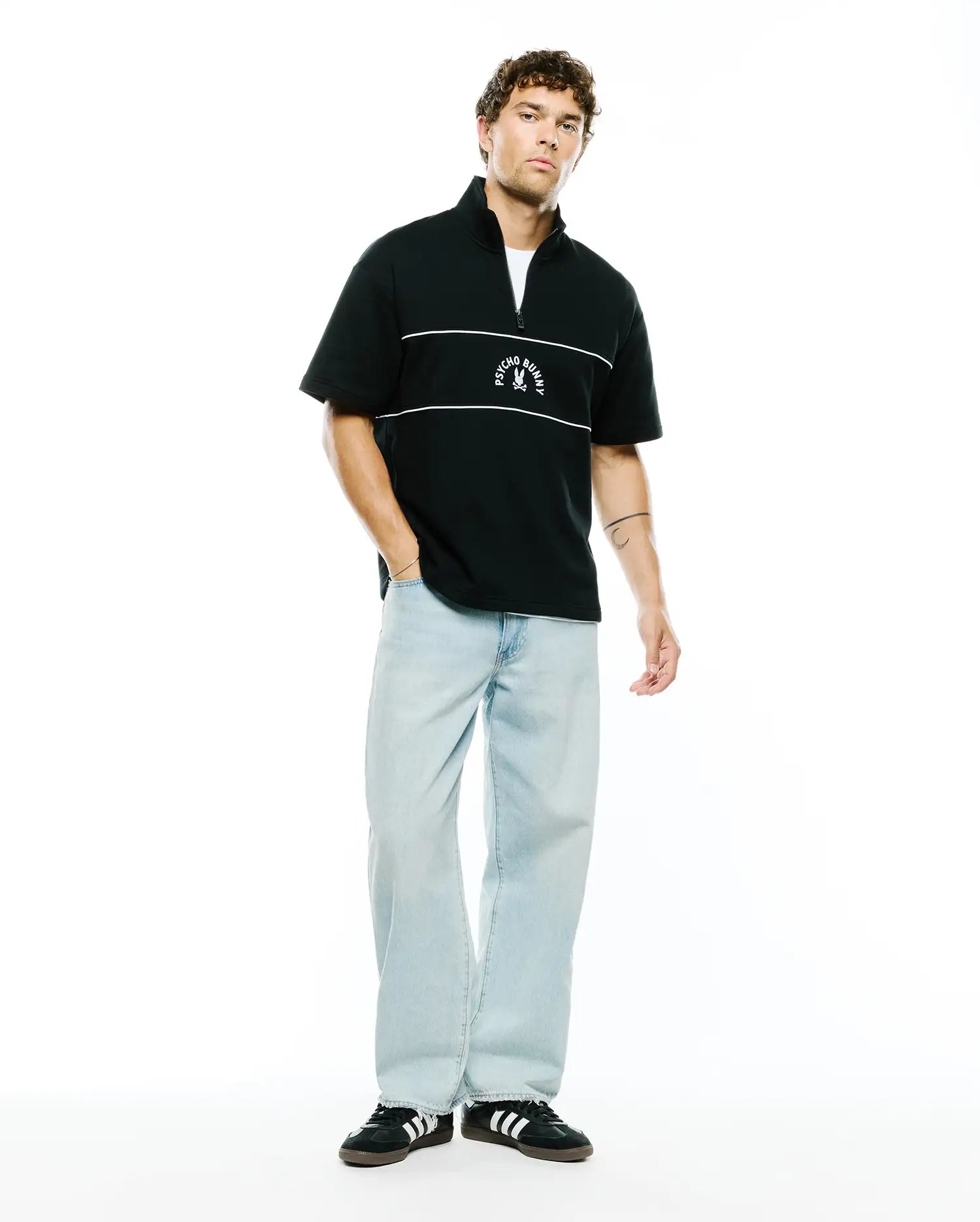 Mens Stevie French Terry Ss 1/4 Zip in black, featuring a relaxed fit, soft french terry fabric, two white horizontal chest stripes, and a white Psycho Bunny skull logo centered on the chest.