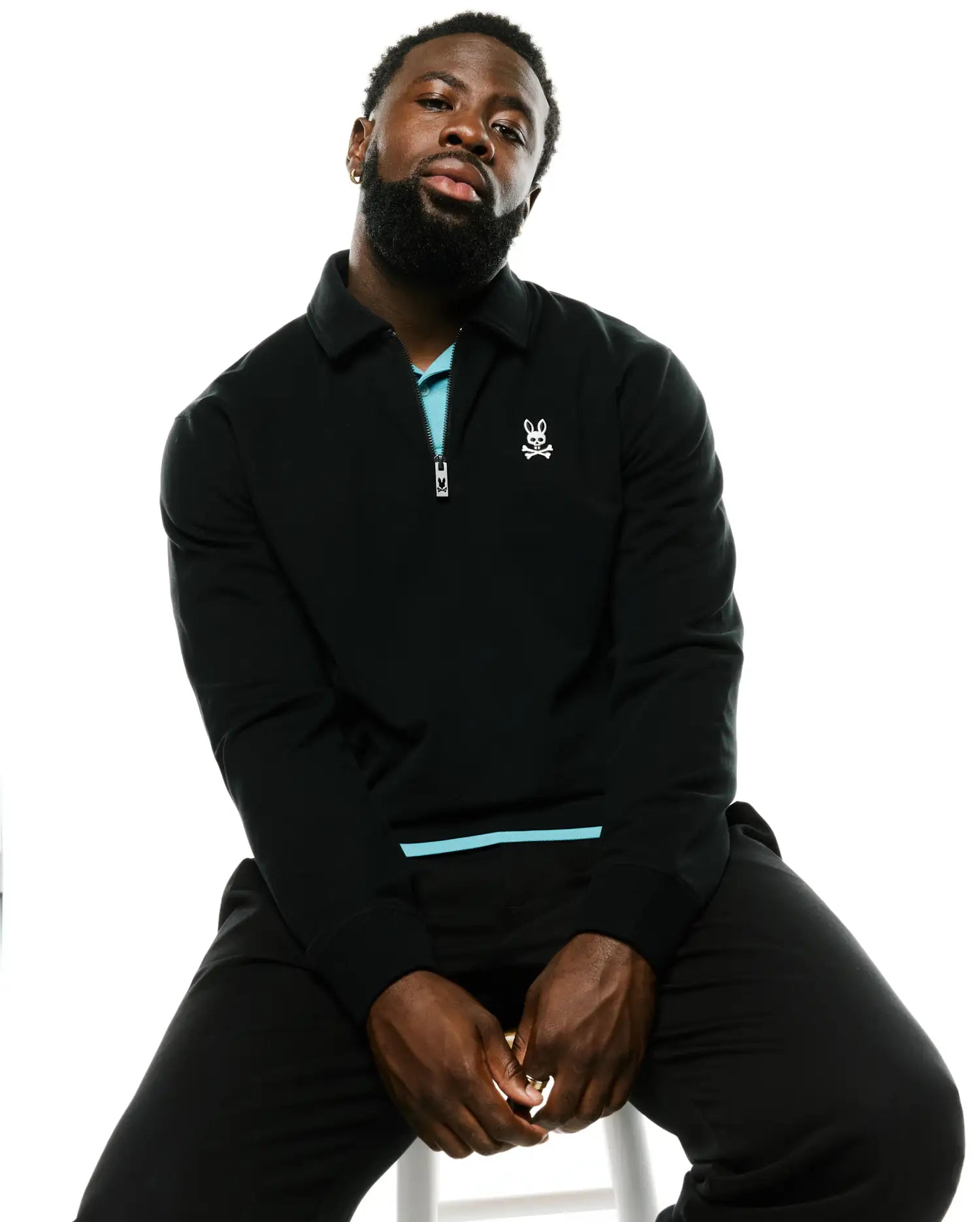 Black classic fit Men's Samson Quarter-Zip Sweater in a smooth knit, featuring a light blue inner collar, quarter-zip with logo pull, and small white embroidered Psycho Bunny skull on the left chest. (4)