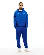 Royal blue MENS NATHANIEL RELAXED CHEST HOODIE and matching sweatpants, crafted from soft french terry, featuring white Psycho Bunny text and multiple bunny skull logos on the chest, plus a single bunny skull on the left thigh. (2)