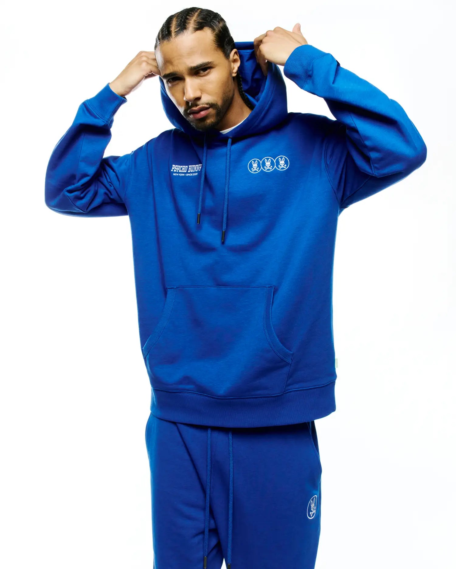 Mens Nathaniel Relaxed Chest Hoodie in royal blue soft fleece, featuring a white Psycho Bunny text logo on the left chest and three small white bunny skull logos on the right chest, with a kangaroo pocket and drawstrings. (4)