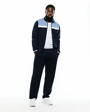Men's Jacques Pique Track Jacket in navy, featuring a classic fit, light blue and white color-block chest panels, a white embroidered Psycho Bunny script logo on the left chest, and striped ribbed cuffs. (1)