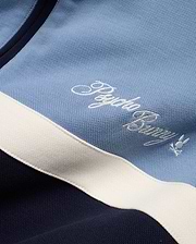 Men's Jacques Pique Track Jacket in light blue and navy pique fabric with a white stripe, featuring an embroidered white Psycho Bunny script logo and small bunny skull logo on the chest. (6)