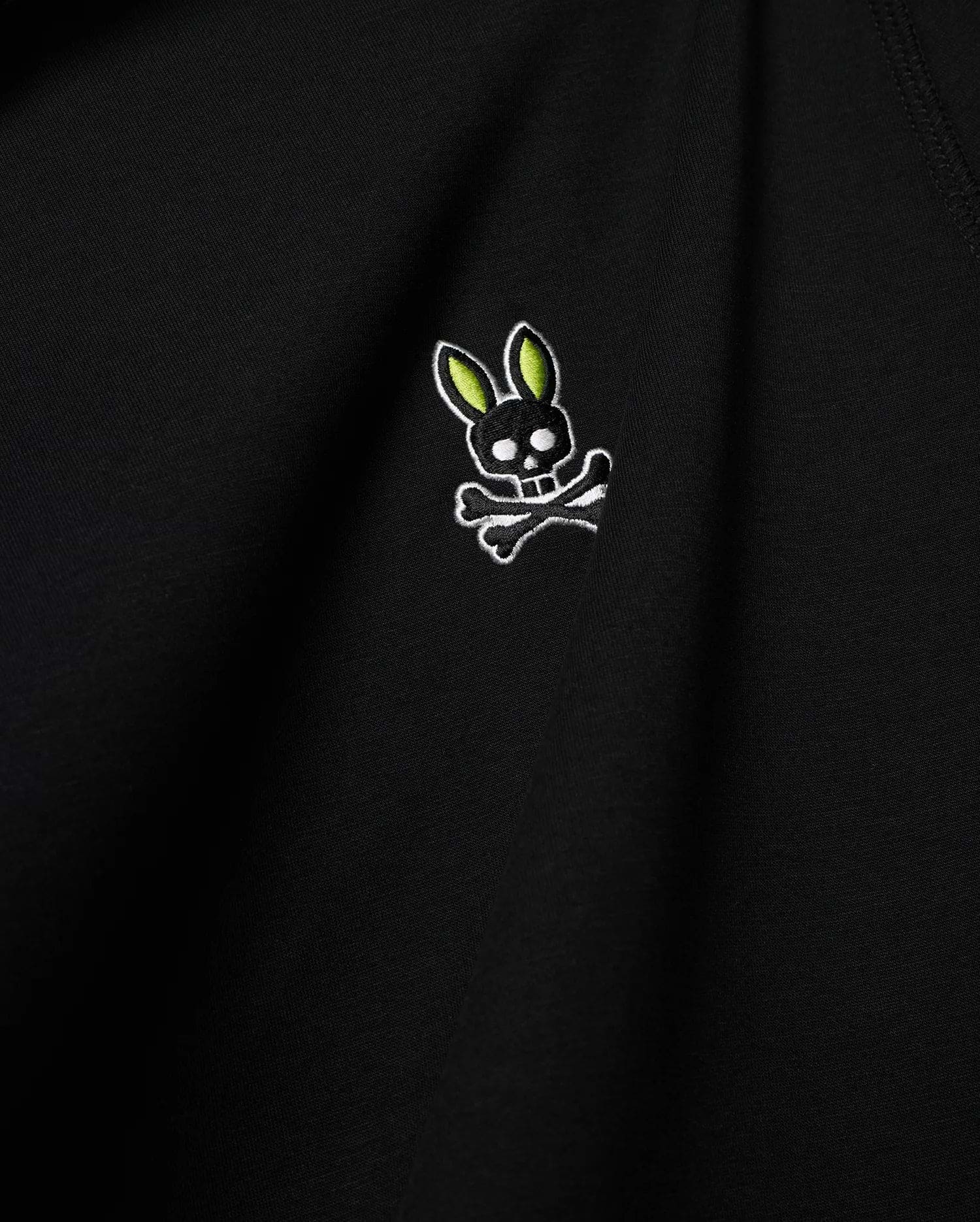 Mens Lex Hoodie, black smooth knit, featuring a small embroidered Psycho Bunny skull logo on the chest with vibrant neon green ears, black skull, and white outline details. (6)