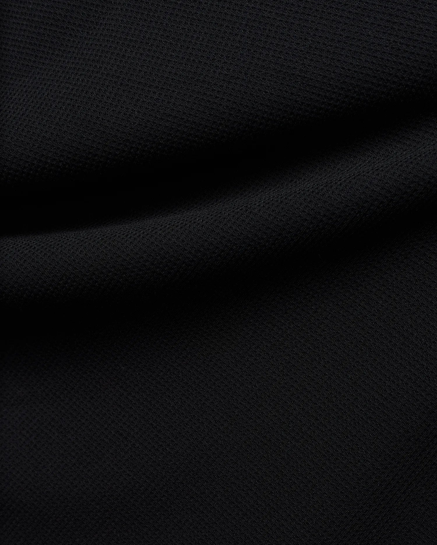 Premium black Tomas Waffle 1/4 Zip, showcasing its rich, deep black fabric with a prominent, textured waffle knit pattern and soft, flowing folds, embodying Psycho Bunny's refined streetwear.