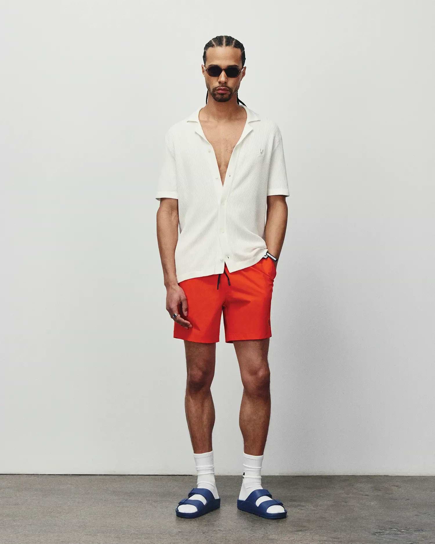 Mens Samos Hydrochromic Printed Swim Trunk in vibrant orange, classic fit, paired with a relaxed white ribbed knit short-sleeve collared shirt featuring a small embroidered Psycho Bunny logo on the left chest. (4)