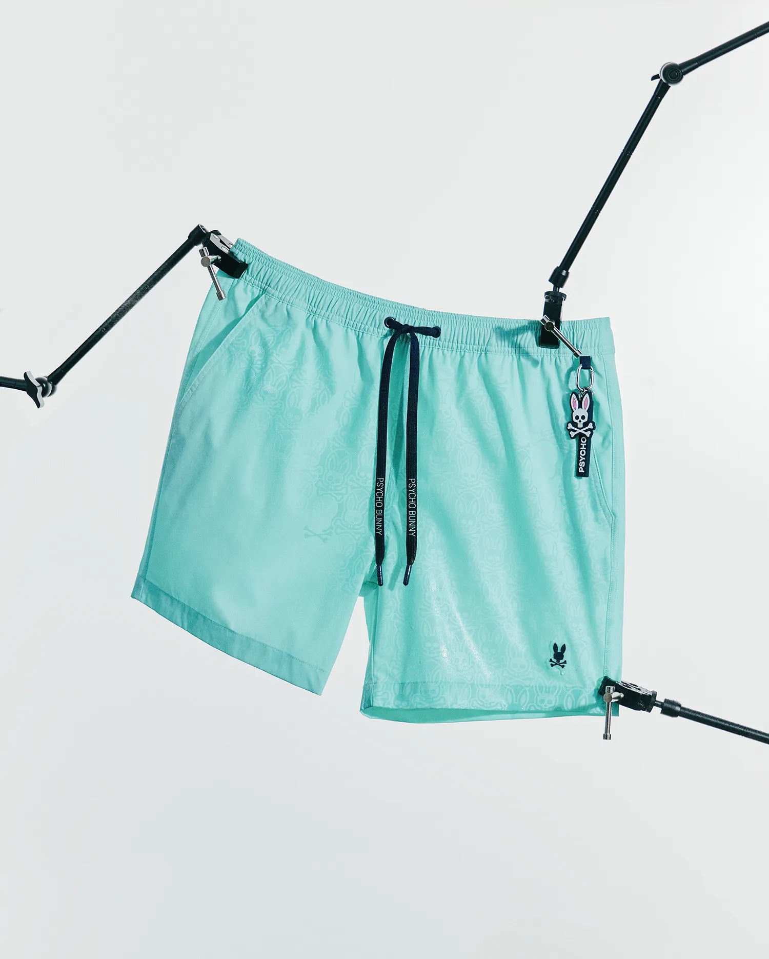 Mens Samos Hydrochromic Printed Swim Trunk 6 in aqua, featuring a subtle hydrochromic bunny skull print, black Psycho Bunny drawstrings, and an embroidered bunny skull logo. (6)
