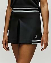A person is wearing the Psycho Bunny WOMENS KNIT SKORT - WO1900001 in black, featuring white stripes at the waistband and hem, plus a small white skull and bunny logo near the bottom. The top of a black shirt is also visible. (1)