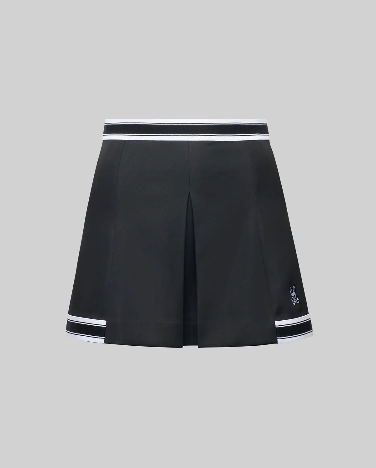 The WOMENS KNIT SKORT - WO1900001 by Psycho Bunny is a black pleated mini skort with white striped trim at the waistband and hem, plus a small white Psycho Bunny logo near the left hem, shown on a plain gray background. (6)