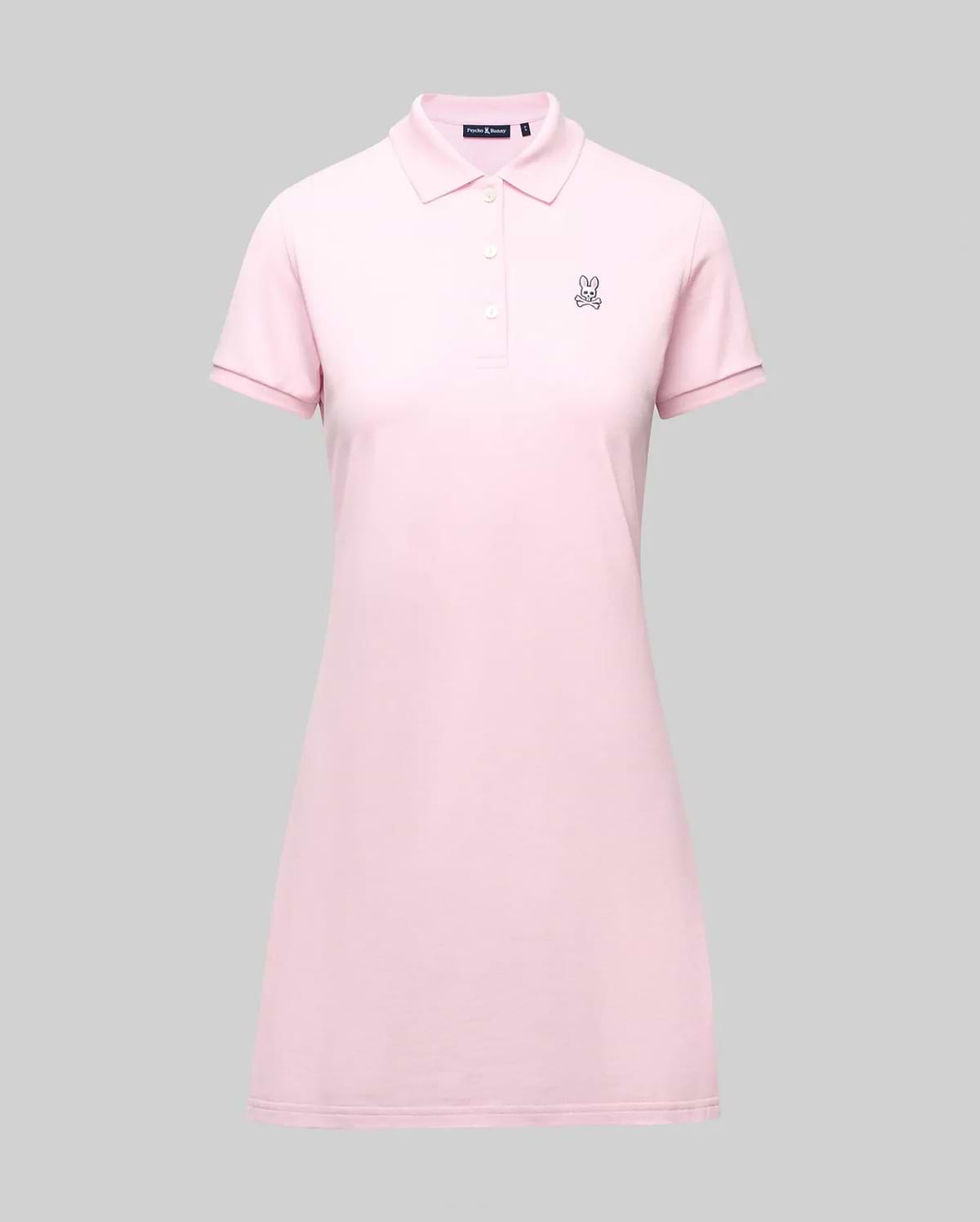 The Psycho Bunny WOMENS POLO DRESS - WO2000003 is a light pink Pima polo dress with a feminine fit, collar, three Mother-of-Pearl buttons, and a small embroidered bunny logo on the left chest, shown on a plain gray background. (7)