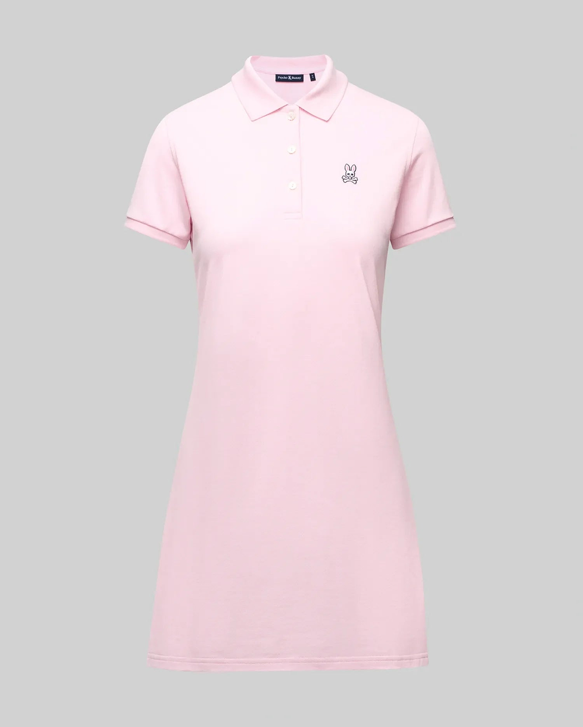 The Psycho Bunny WOMENS POLO DRESS - WO2000003 is a light pink Pima polo dress with a feminine fit, collar, three Mother-of-Pearl buttons, and a small embroidered bunny logo on the left chest, shown on a plain gray background. (7)