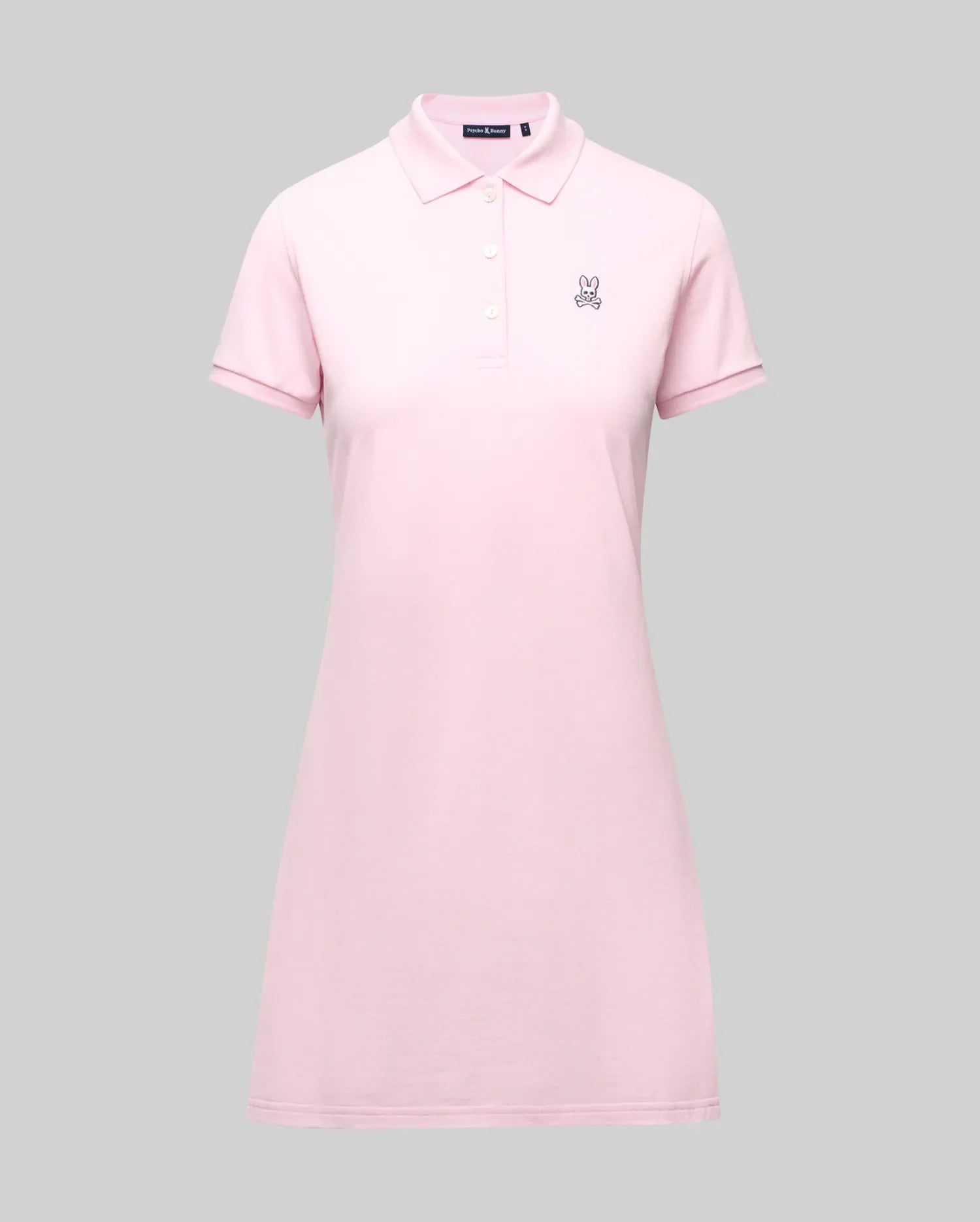 The Psycho Bunny WOMENS POLO DRESS - WO2000003 is a light pink Pima polo dress with a feminine fit, collar, three Mother-of-Pearl buttons, and a small embroidered bunny logo on the left chest, shown on a plain gray background. (7)