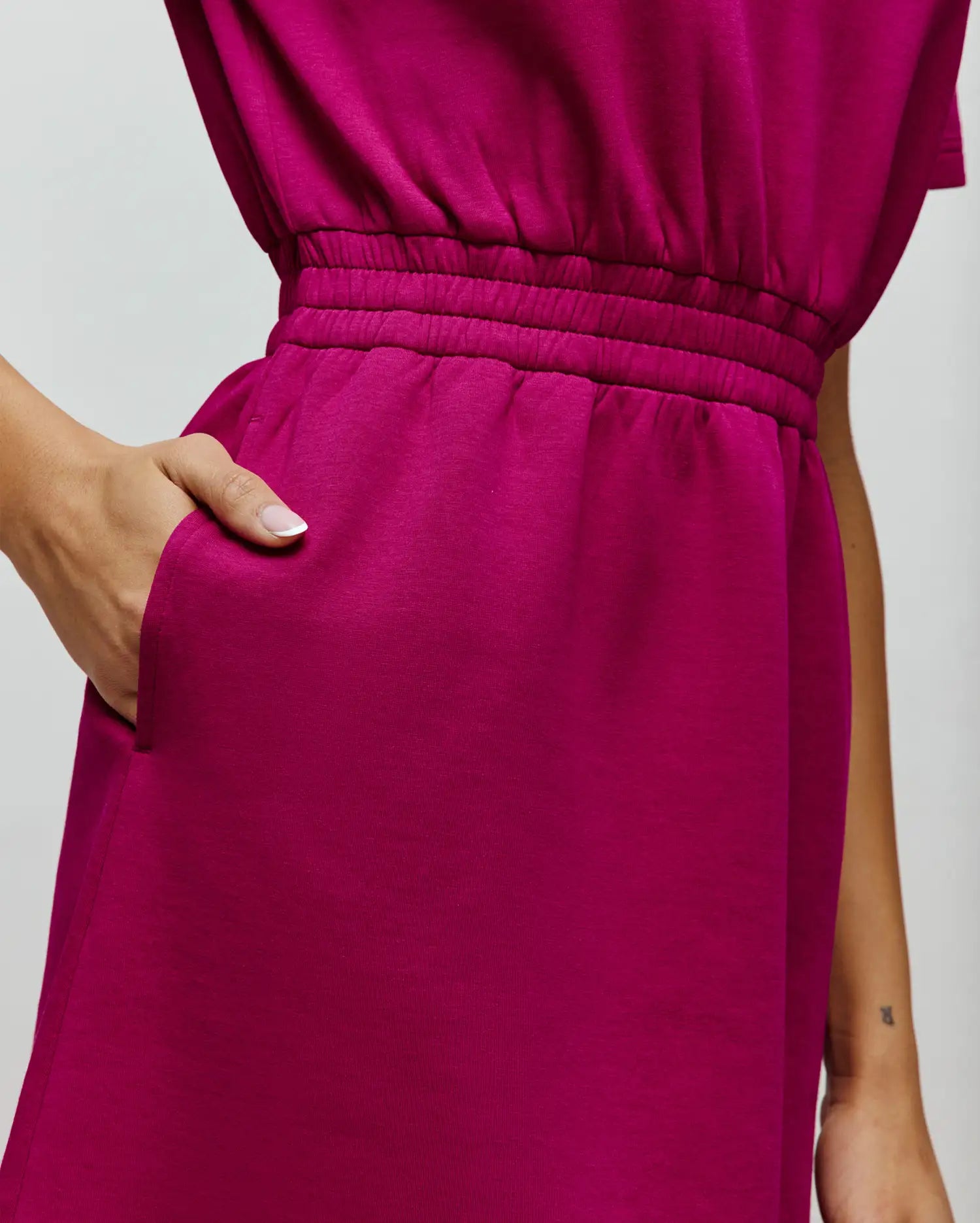 Womens Penelope Dress in vibrant magenta jersey knit, featuring a comfortable elasticated waist and practical side pockets, offering a relaxed yet defined fit. (3)