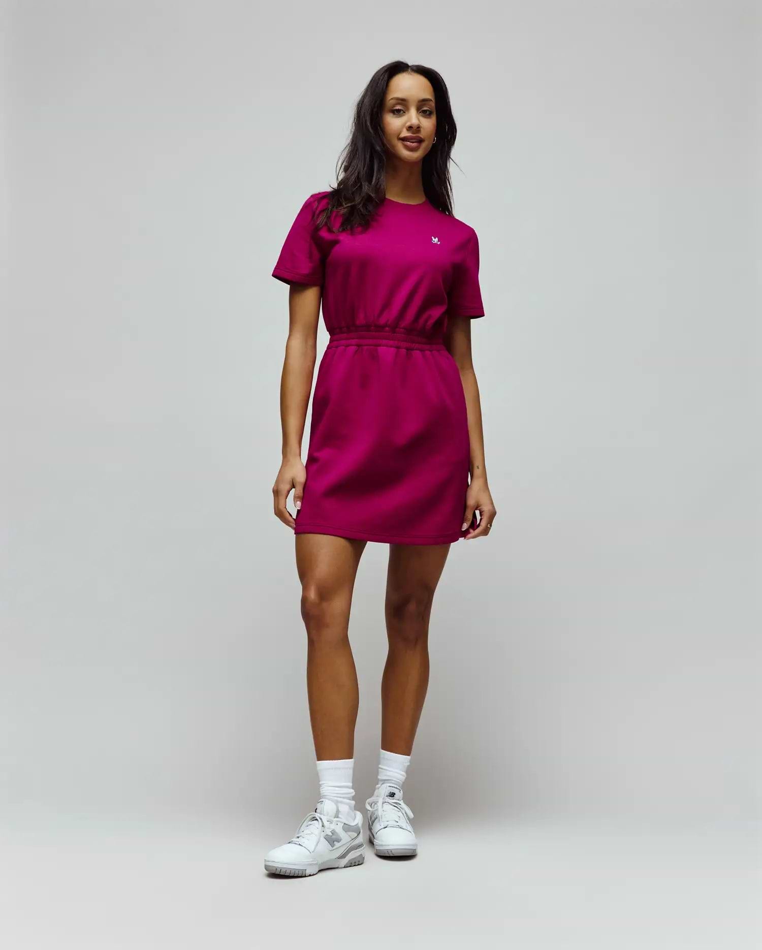 Womens Penelope Dress, a vibrant magenta jersey mini dress with a relaxed fit, crew neck, short sleeves, and an elasticated waist, featuring a small white embroidered Psycho Bunny skull logo on the left chest. (2)