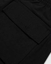 Close-up image of a black fabric pocket with a flap and Velcro closure. The pocket is attached to the KIDS MALTA HYDROCHROMIC SWIM TRUNK - B0W321B2SW by Psycho Bunny, adorned with a playful bunny pattern, and the stitching around the edges is clearly visible. The fabric appears to be smooth and durable.