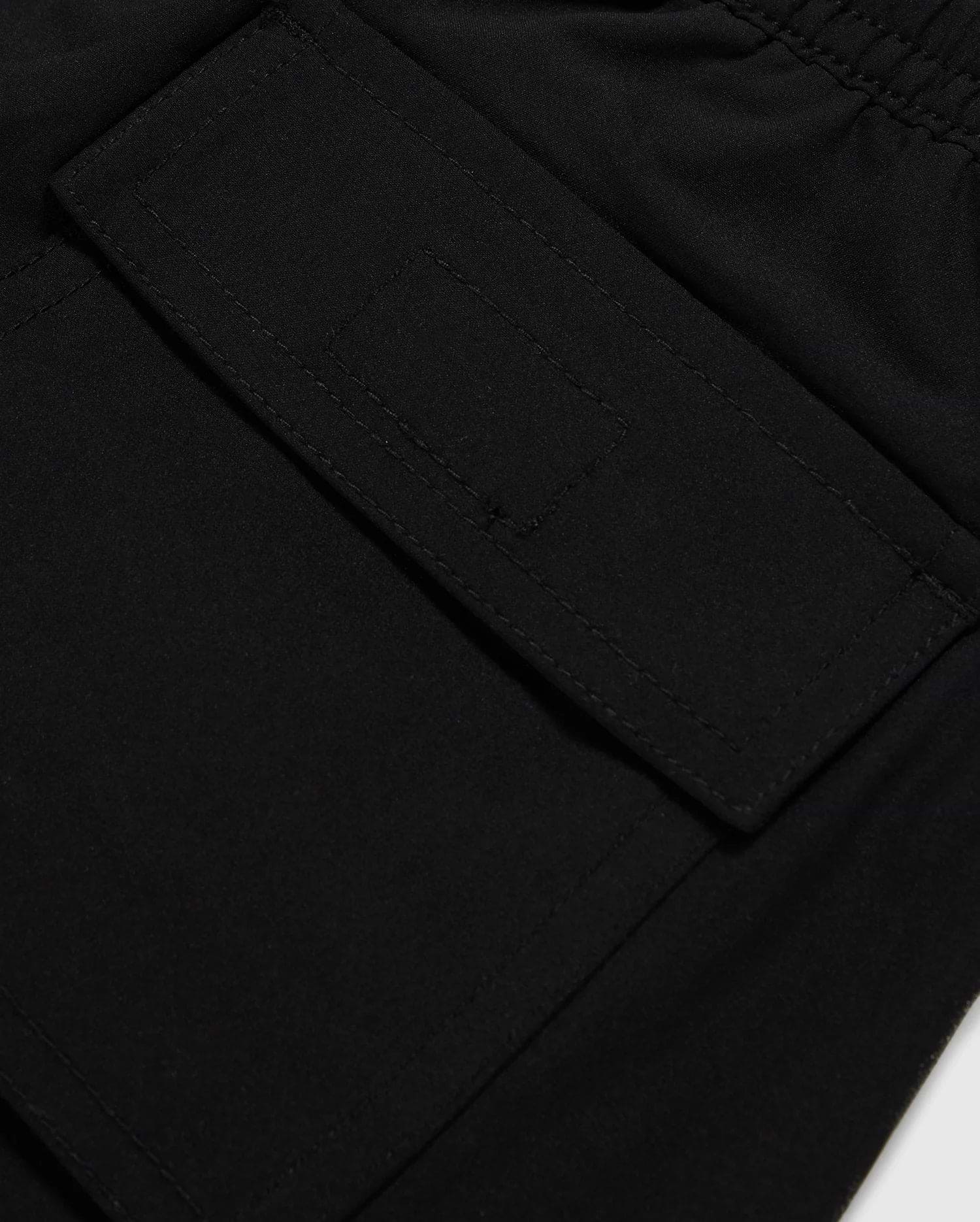 Close-up image of a black fabric pocket with a flap and Velcro closure. The pocket is attached to the KIDS MALTA HYDROCHROMIC SWIM TRUNK - B0W321B2SW by Psycho Bunny, adorned with a playful bunny pattern, and the stitching around the edges is clearly visible. The fabric appears to be smooth and durable.