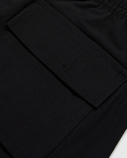 Close-up image of a black fabric pocket with a flap and Velcro closure. The pocket is attached to the KIDS MALTA HYDROCHROMIC SWIM TRUNK - B0W321B2SW by Psycho Bunny, adorned with a playful bunny pattern, and the stitching around the edges is clearly visible. The fabric appears to be smooth and durable.