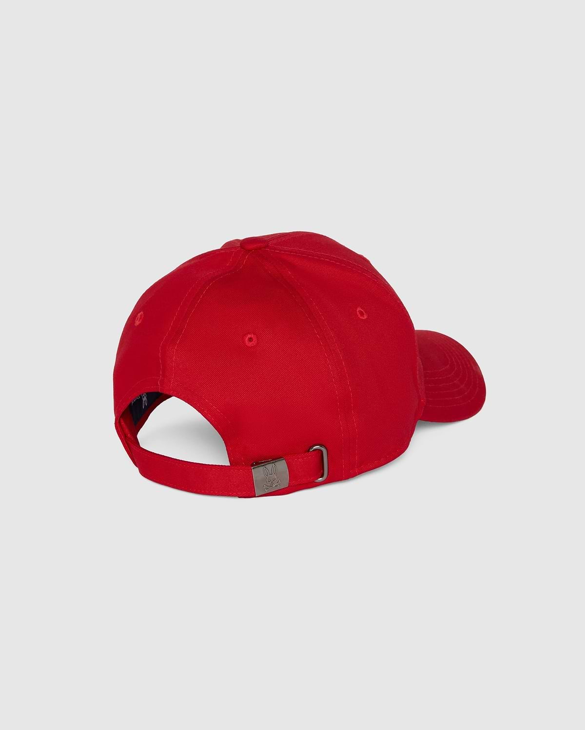 The Psycho Bunny MENS CLASSIC BASEBALL CAP - B6A816A1HT is red with a curved brim, made of six-panel cotton twill, adjustable via a metal buckle strap, and showcases an embroidered Bunny logo. It's shown from the back against a plain gray backdrop.