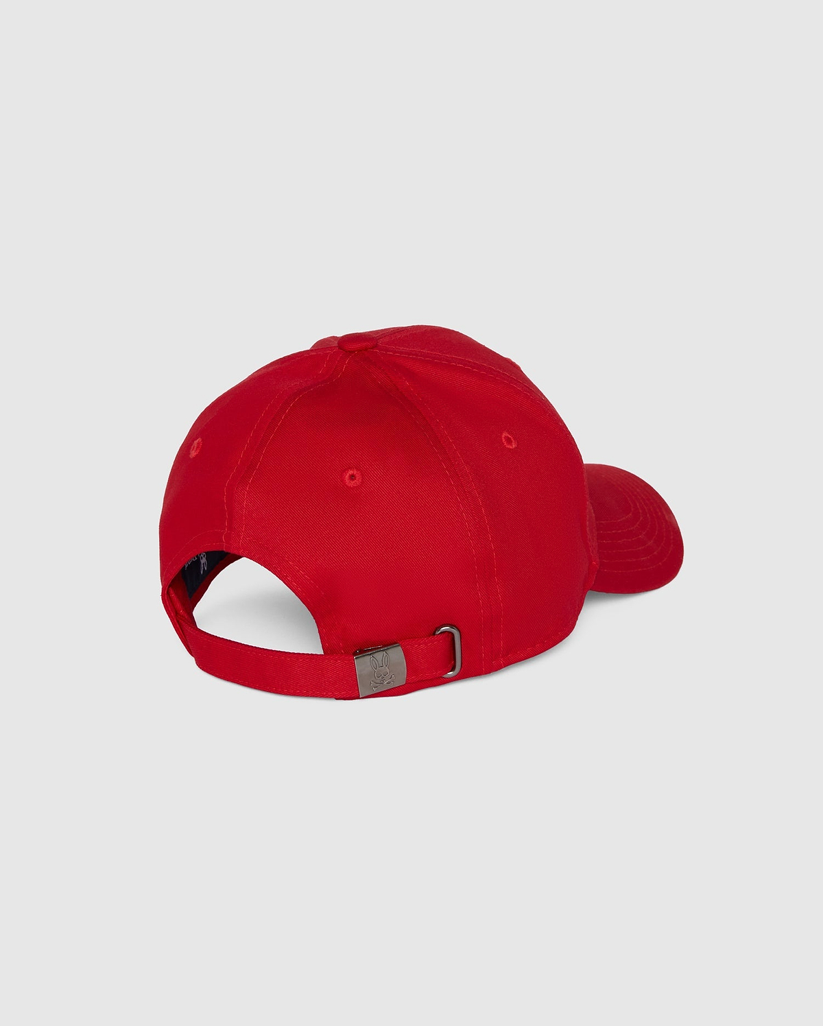 The Psycho Bunny MENS CLASSIC BASEBALL CAP - B6A816A1HT is red with a curved brim, made of six-panel cotton twill, adjustable via a metal buckle strap, and showcases an embroidered Bunny logo. It's shown from the back against a plain gray backdrop.