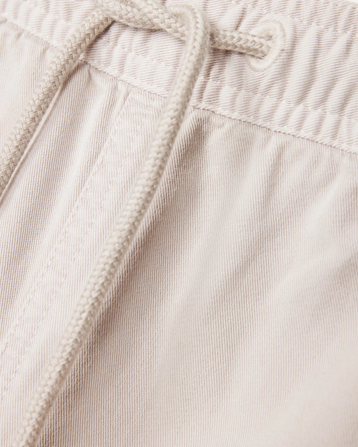 Close-up of the light beige Psycho Bunny MENS WILLIS STRETCH TENCEL SHORT - B6R239Y1WB, featuring an elasticated waistband with a drawstring. The fabric texture and stitching details are clearly visible, exemplifying the perfect combination of style and comfort.