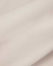 Close-up of the light beige fabric from the Psycho Bunny MENS WILLIS STRETCH TENCEL SHORT - B6R239Y1WB, featuring a smooth, slightly ribbed texture that is perfect for men's trousers. The material looks soft and supple, gently folded in overlapping layers to highlight its subtle sheen and fine weave pattern.