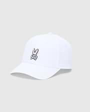 The KIDS CLASSIC BASEBALL CAP - B0A816A1HT by Psycho Bunny is a white cap with a curved brim and adjustable fit, featuring a pink and white embroidered bunny above crossed bones on the front, set against a plain gray background.