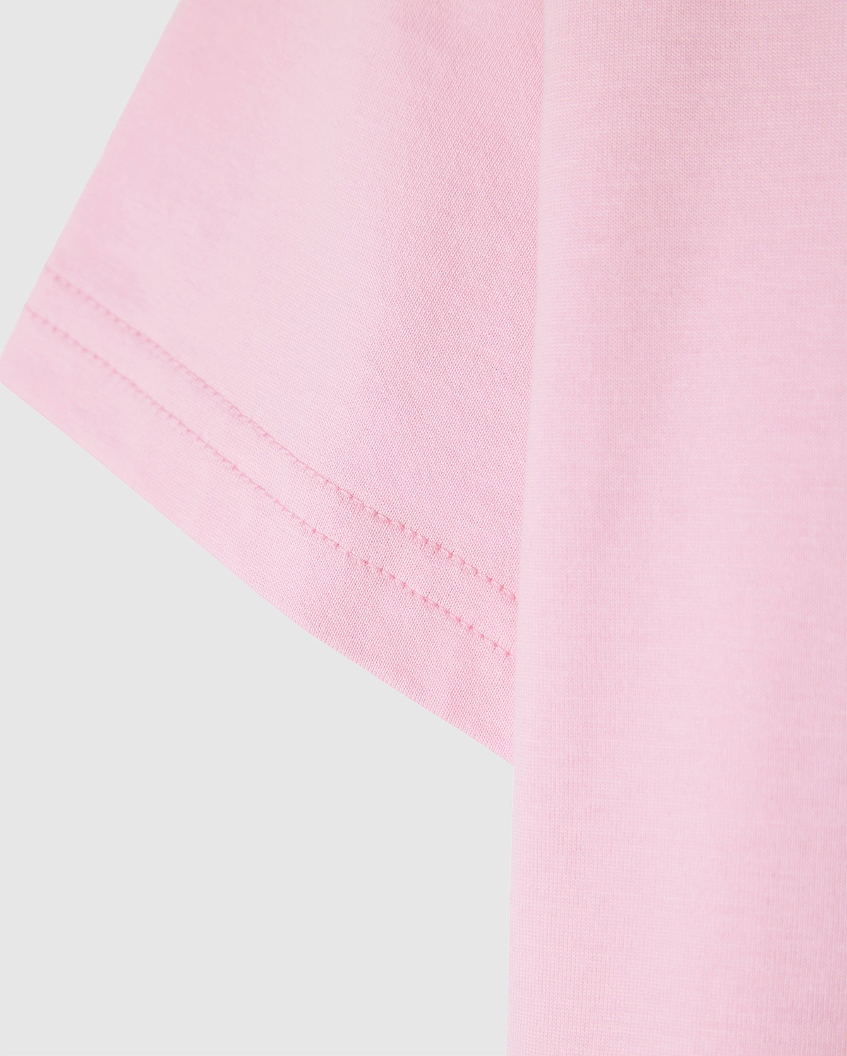 Close-up of the sleeve of a light pink Psycho Bunny KIDS CLASSIC CREW NECK TEE - B0U014CRPC against a plain background, showcasing the 100% Pima cotton fabric texture and stitching detail. An ideal pick for back-to-school outfits.