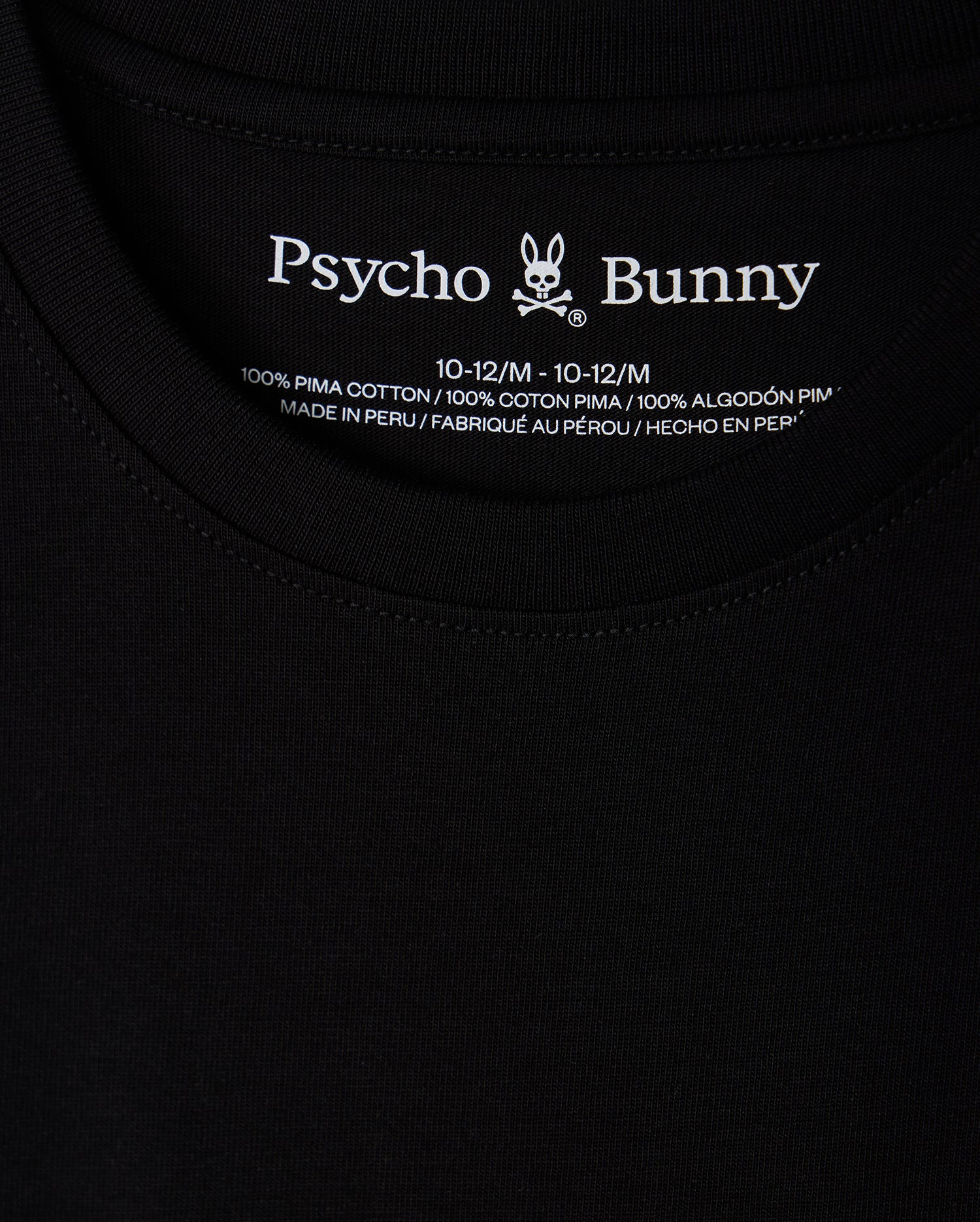 Close-up of a black KIDS HAWAII CITY TEE (B0U169Y1PC) by Psycho Bunny, crafted from Pima cotton with the brand name and bunny logo at the neckline. Includes size and fabric details, highlighting it's made in Peru, paralleling the volcanic islands' rich natural beauty.