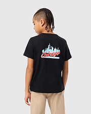 A child with braided hair stands facing away, wearing the Psycho Bunny KIDS CHICAGO CITY TEE - B0U551W1PC, a black t-shirt crafted from soft Pima cotton jersey and showcasing the word "Chicago" along with a skyline graphic. Light-colored pants complete this casual look.
