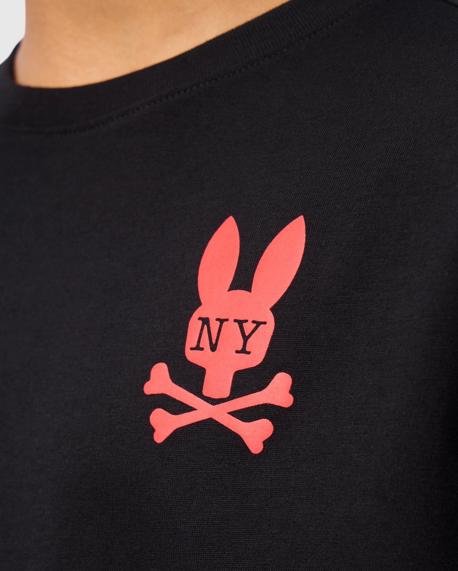 Close-up of a black Psycho Bunny KIDS NEW YORK CITY TEE - B0U554W1PC, crafted from premium Pima cotton and featuring a red logo with a stylized rabbit head above crossed bones. The letters "NY" are printed on the rabbit's face, making this tee both stylish and comfortable for kids.