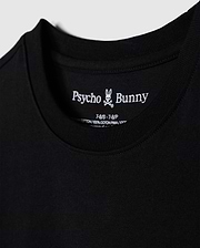 Close-up of a black t-shirt, showcasing the brand name "Psycho Bunny" and a small bunny skull logo inside the collar. Details include shirt size and material info, made from 100% Peruvian Pima cotton. The soft and smooth fabric highlights its premium quality. This particular piece is identified as the "KIDS LOS ANGELES CITY TEE - B0U861A2PC".