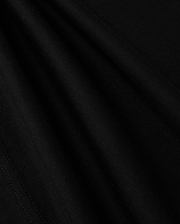 A close-up view of the smooth, dark fabric of the KIDS LOS ANGELES CITY TEE - B0U861A2PC by Psycho Bunny shows a fine, consistent weave. The folds create subtle shadows and highlights, accentuating the texture and soft appearance of this luxurious Peruvian Pima cotton material, suggesting it is well-crafted and of high quality.