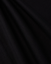 A close-up view of the smooth, dark fabric of the KIDS LOS ANGELES CITY TEE - B0U861A2PC by Psycho Bunny shows a fine, consistent weave. The folds create subtle shadows and highlights, accentuating the texture and soft appearance of this luxurious Peruvian Pima cotton material, suggesting it is well-crafted and of high quality.