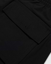 Close-up of a black polyester mechanical stretch fabric with a detailed view of a stitched rectangular patch pocket on Psycho Bunny's KIDS MALTA HYDROCHROMIC SWIM TRUNK - B0W321B2SW.