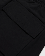 Close-up of a black polyester mechanical stretch fabric with a detailed view of a stitched rectangular patch pocket on Psycho Bunny's KIDS MALTA HYDROCHROMIC SWIM TRUNK - B0W321B2SW.