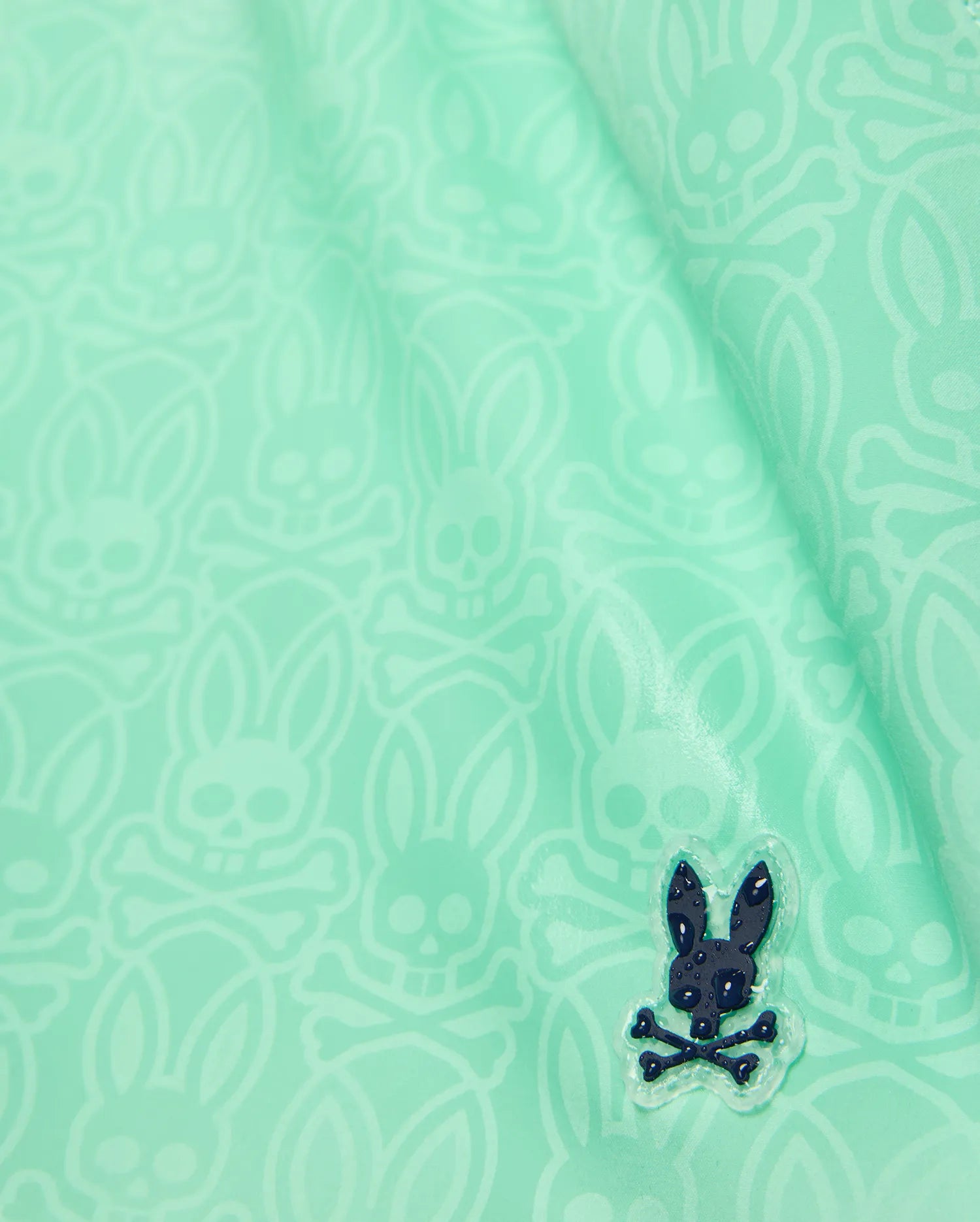 Kids Samos Hydrochromic Printed Swim Trunk in mint green, featuring a subtle all-over tone-on-tone Psycho Bunny skull print and a raised dark navy rubberized bunny logo with water droplets.